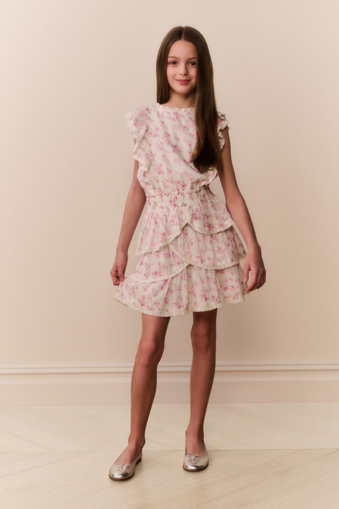 Girl wearing a floral ruffle dress against a plain background