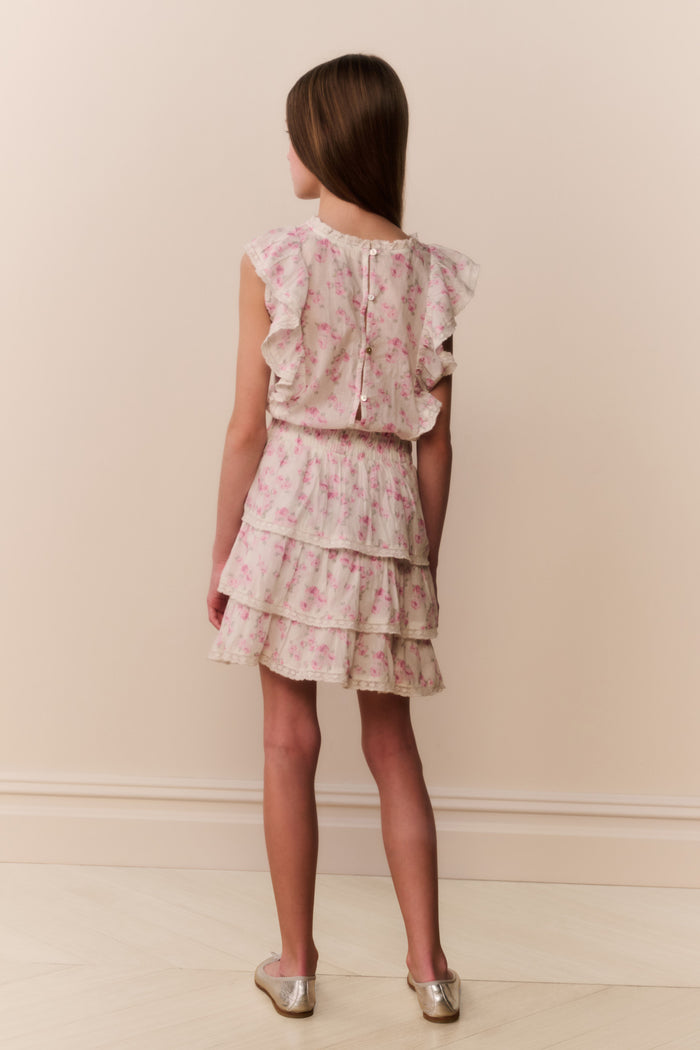 Girl wearing a floral ruffle dress against a plain background