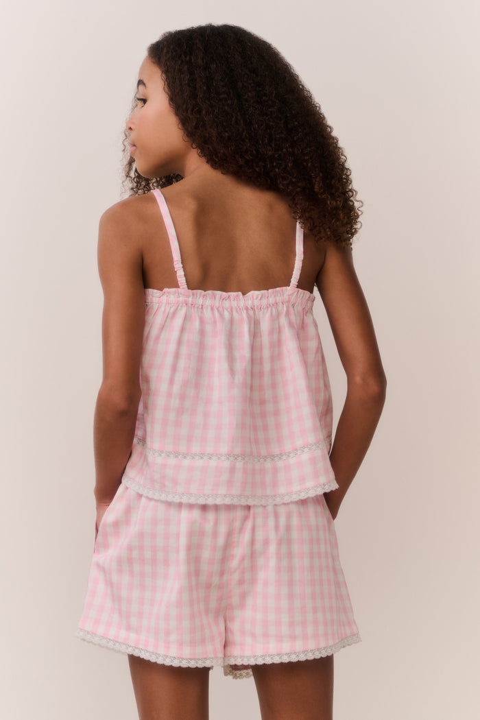 Tween wearing a pink checkered outfit against a plain background