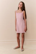 Young girl wearing pink sleeveless mini dress with scalloped lace neckline