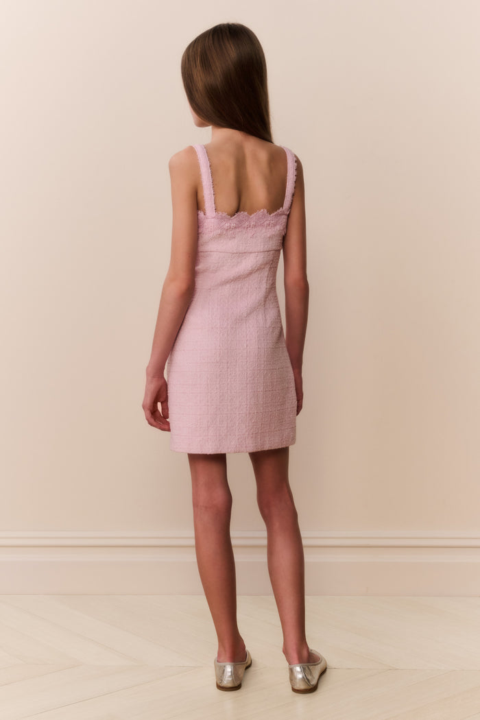 Young girl wearing pink sleeveless mini dress with scalloped lace neckline