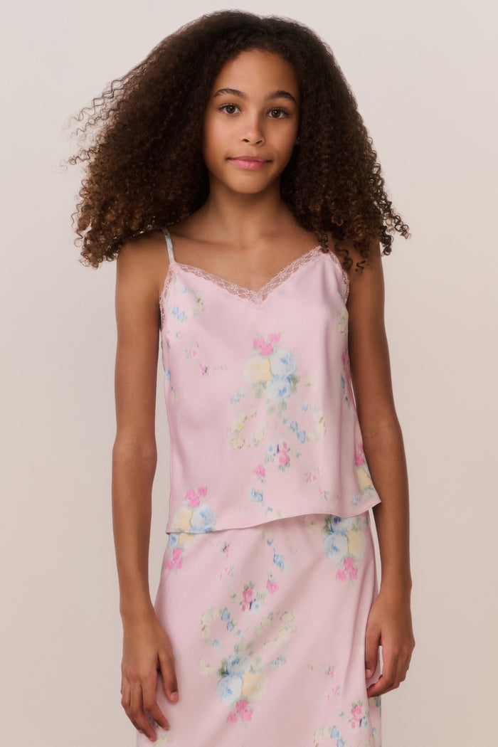 Young girl wearing a pink floral set against a plain background