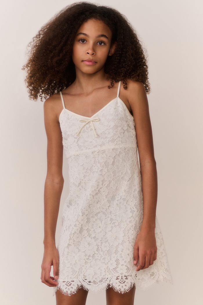 Girl wearing a white lace dress against a plain background