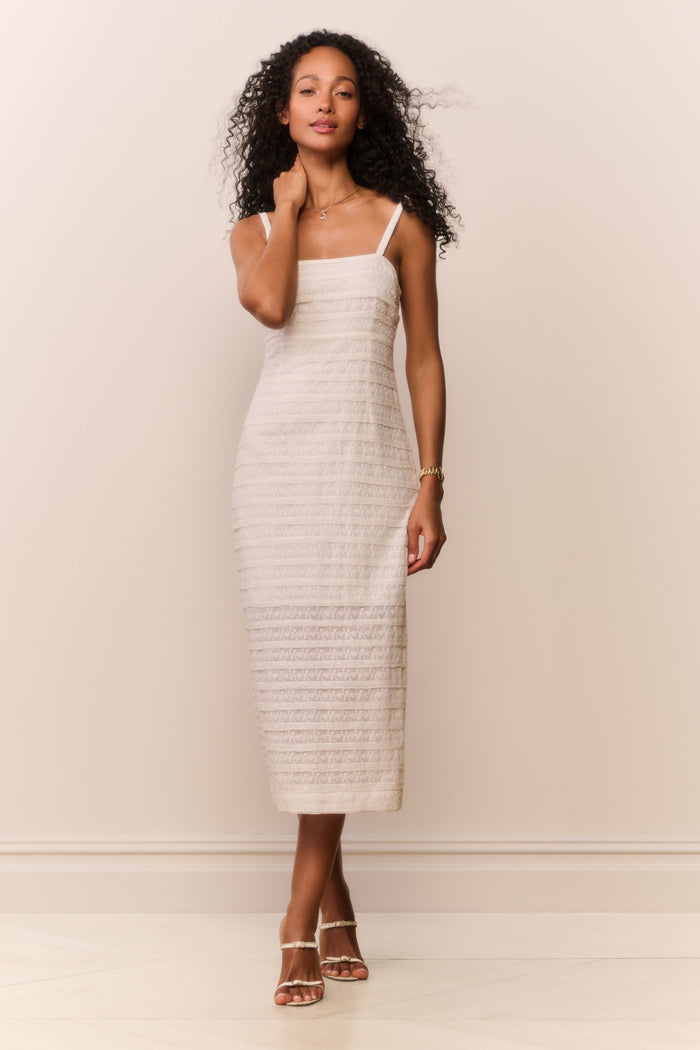 Woman wearing a white textured sleeveless dress against a plain background