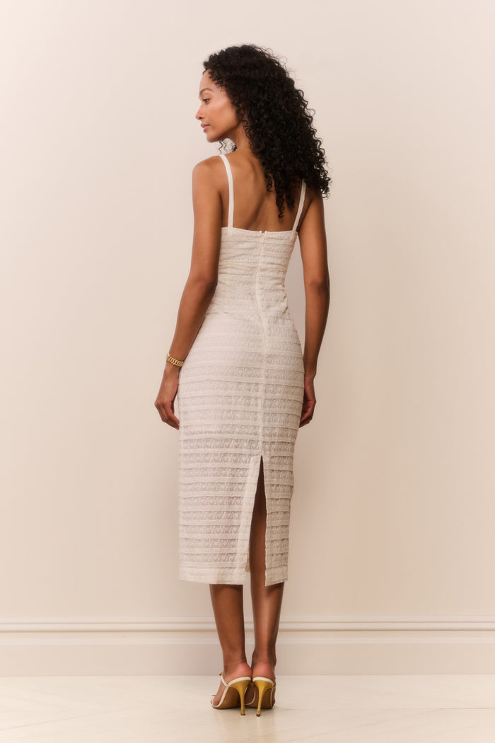 Woman wearing a white textured sleeveless dress against a plain background