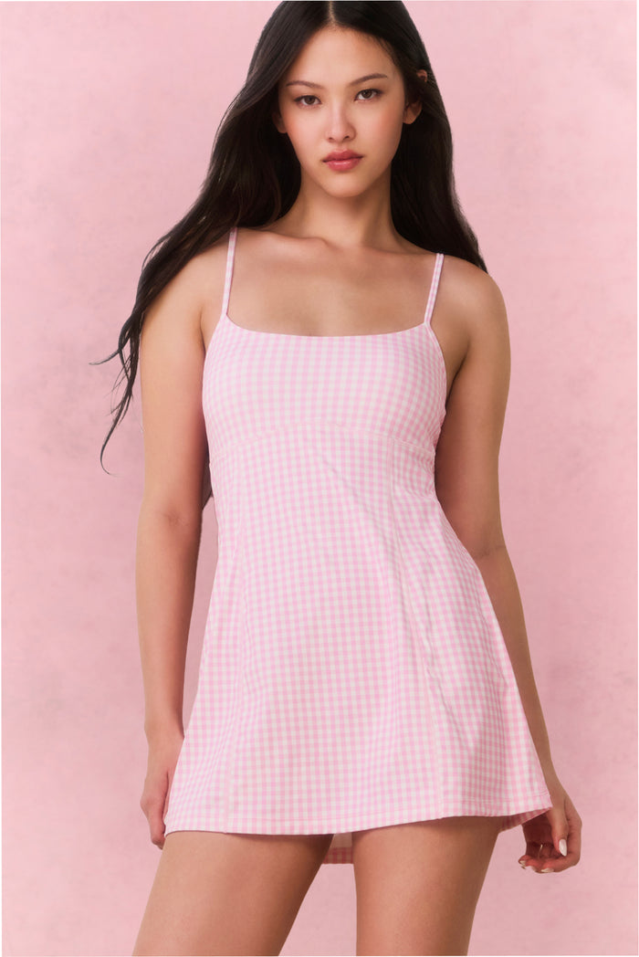 Woman wearing a pink checkered dress against a pink background