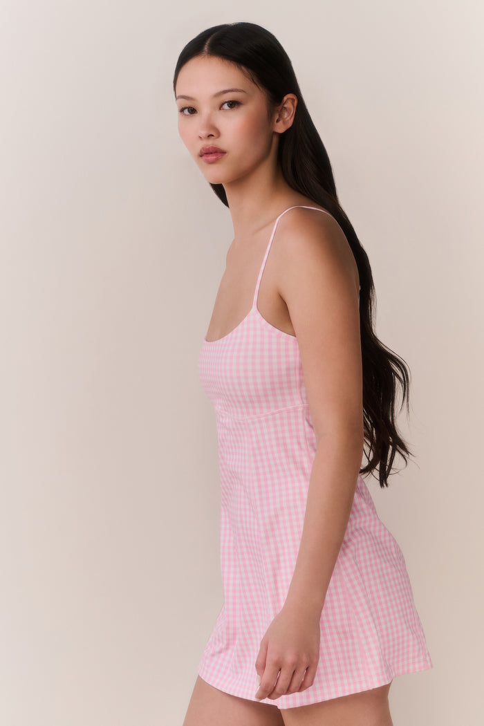Woman wearing a pink checkered dress against a plain background