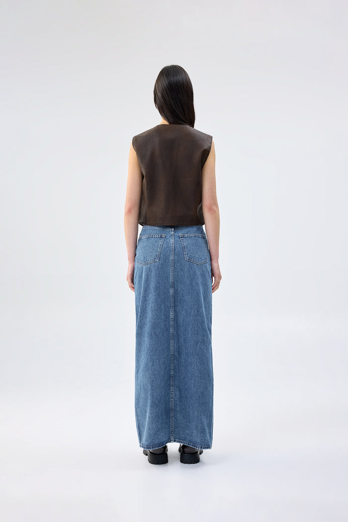 Model wearing a brown sleeveless top and blue denim skirt on a white background